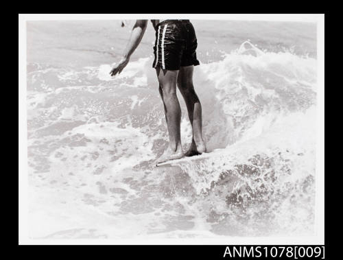 Man's legs while riding a surfboard