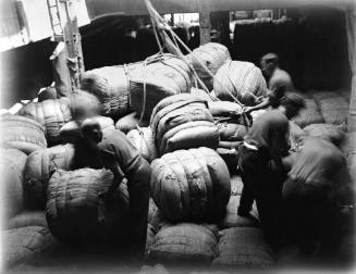Crew men packing bales of wool into the hold of MAGDALENE VINNEN