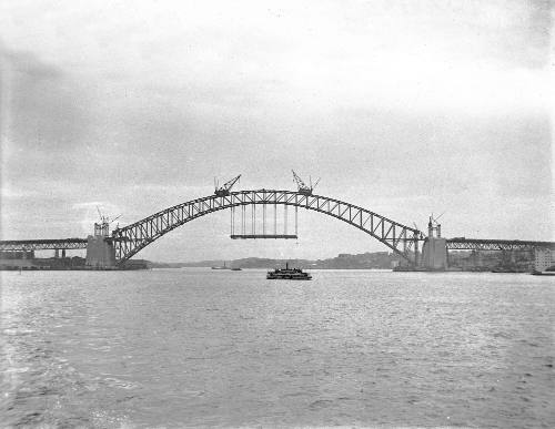 View of Sydney Harbour bridge under construction from east side harbour looking west