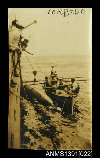 Photograph depicting a torpedo being hoisted