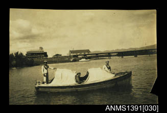 Photograph depicting three men in Navy uniforms on a small boat