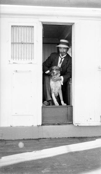 Seaman and pet dog, in deckhouse doorway