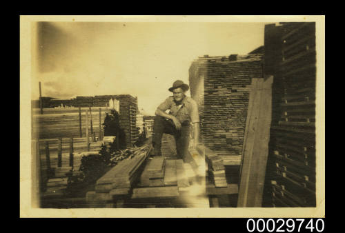 A timber worker leaning on a pile of timber