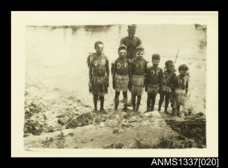 Children and man in native dress with paint on part of their bodies