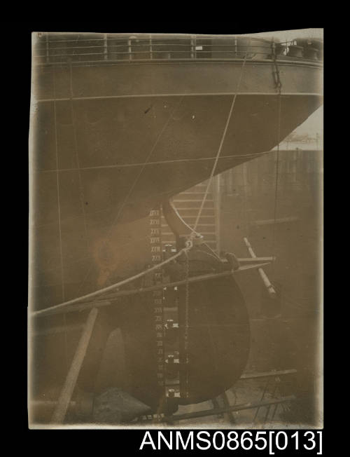 Photograph depicting the portside view of rudder of twin screw steamer in dry dock