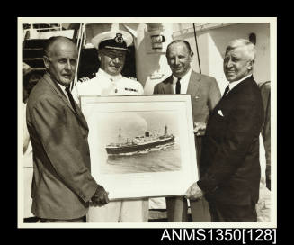 Photograph of four men holding a framed picture of SS ARAMAC