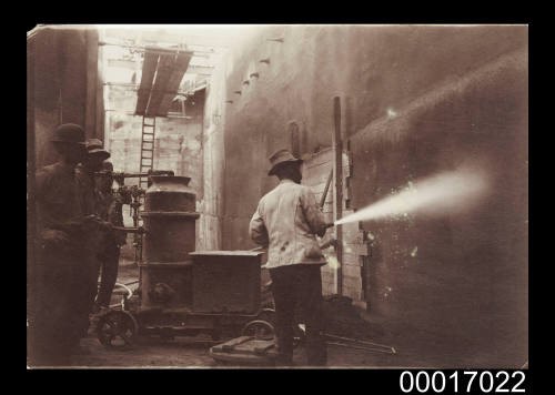 Man using a high pressure water jet to clean ship's hull