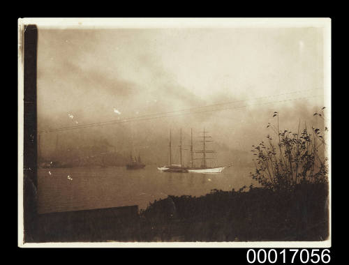 Four masted sailing ship at anchor on Sydney Harbour with factories in the distance