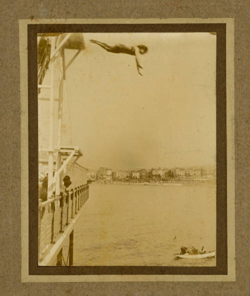 Beatrice Kerr diving from a platform above a pier