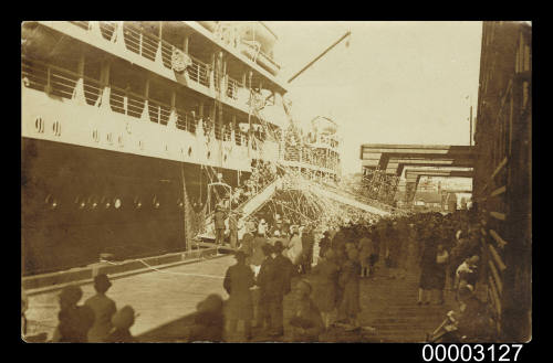 Passengers throwing streamers from a liner to the wharf below