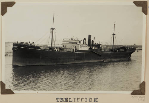 Photograph of  TRELISSICK depicting port side of cargo ship, in harbour with line to ?tug at bow, centre left [Tug not seen]