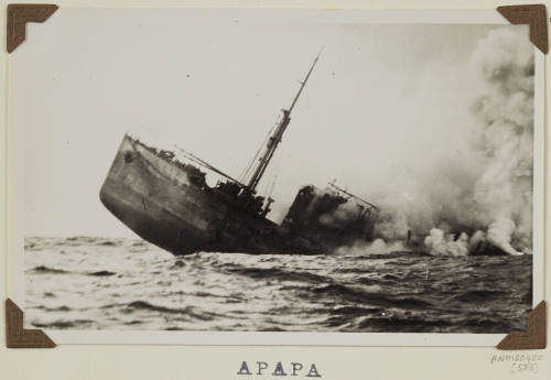 Photograph of  APAPA depicting part of  port side bow of  vessel sinking at sea with midship afire and rest of vessel under water