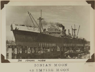 Photograph of  IONIAN MOON depicting bow and port side view of cargo ship berthed at low wooden wharf on port side