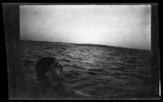 Profile of a man on a vessel, shore in the far distance