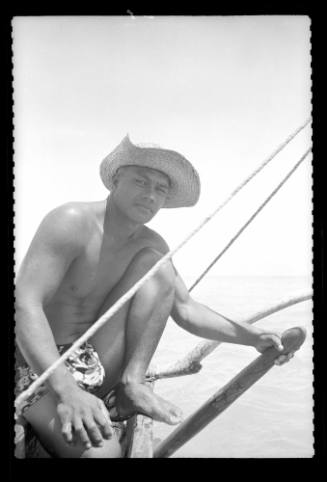 A man wearing a hat and pareu on a sailing craft at Bora Bora