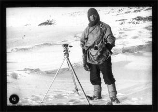 Edward Evans standing next to a sledging theodolite