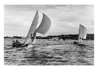 Two 18-foot skiffs racing towards a ferry