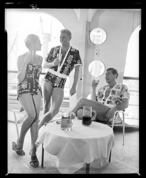 Three models posing on a ship with drinks