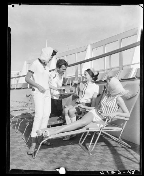 Three models being served drinkings on a ship