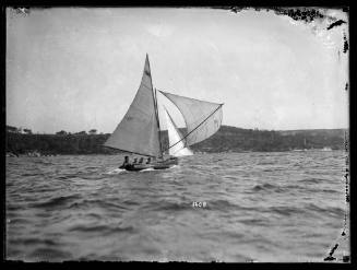 Gaff-rigged skiff carrying a spinnaker sailing on upper harbour