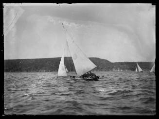 Gaff-rigged skiff on main harbour with V inside an oval sail insignia