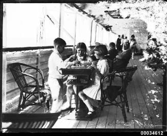 Three children playing a board game possibly on SS ORMISTON