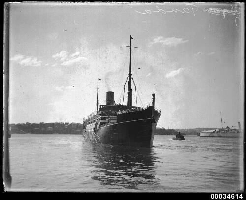 TANDA in harbour with tugboat and warship