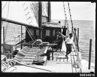 Three men on the deck of a schooner at sea