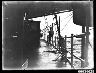 Man seated on the rails of a sailing vessel