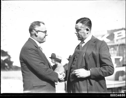 Two men, including Stanley S Crick, shaking hands at a Movietone event