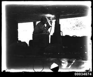 Man welding at the base of a ship, possibly French warship BELLATRIX