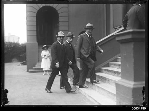 Three civilian officials ascending steps to Parliament House in Sydney