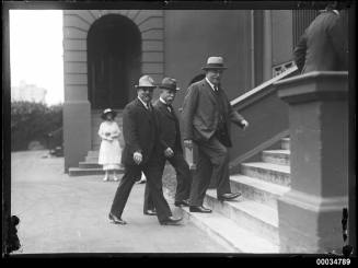 Three civilian officials ascending steps to Parliament House in Sydney