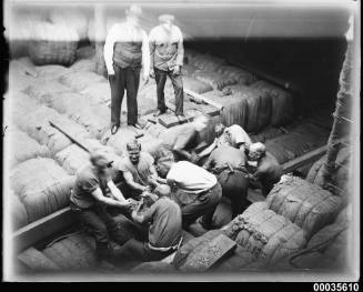 Crew men securing wool bales in the hold of MAGDALENE VINNEN