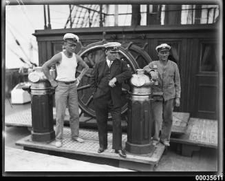 Captain Lorenz Peters with crew members near the ship's wheel on MAGDALENE VINNEN