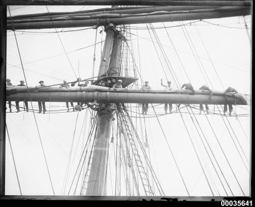 Sailors on spar attending furled sails