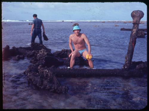 Person sitting on a large anchor belonging to a shipwrecked vessel