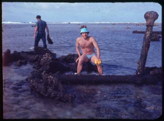 Person sitting on a large anchor belonging to a shipwrecked vessel