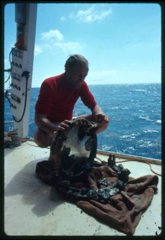 Marine archaeologist Ron Coleman inspecting a piece of a shipwreck on the deck of a vessel