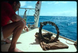 Archaeologist Ron Coleman Inspecting a porthole from a shipwreck on the deck of a vessel