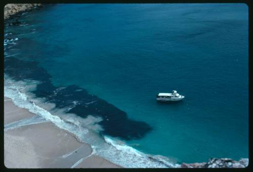 Birds eye view of a sea landscape with a small ship close to shoreline