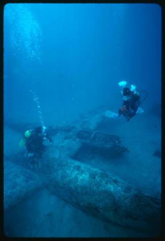 Two divers exploring the wreck of a WW2 U.S bomber plane located in Papua New Guinea