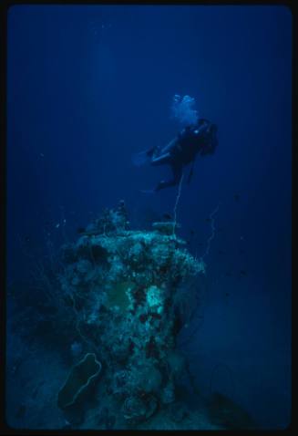 Diver with camera swimming above midget submarine