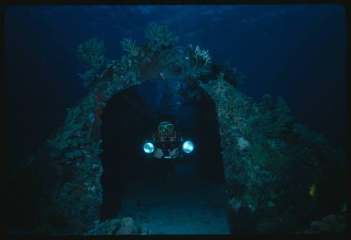 Diver looking through archway of wrecked Conshelf