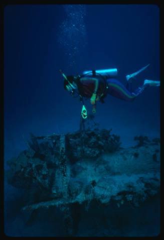 Diver examining wreck of midget submarine on seafloor