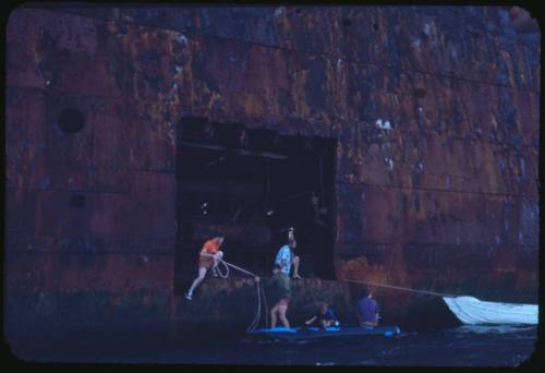 People at the hull of a wrecked vessel