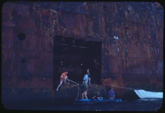 People at the hull of a wrecked vessel