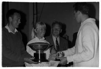 Black and white shot of four people with a trophy being exchanged
