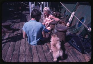 Valerie Taylor and Stuart Cody sitting on the deck of the Terrier VIII with a small dog