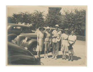 Photograph of group in front of cars